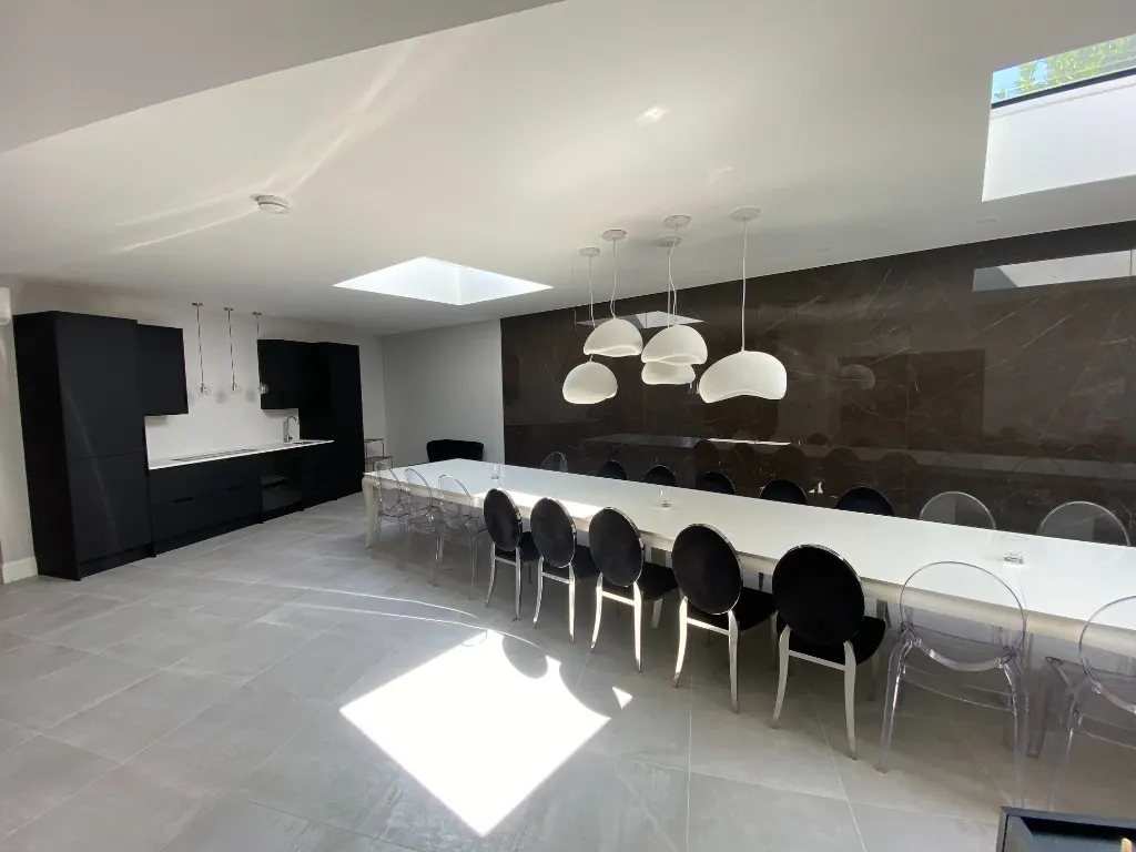 Matte black home bar with white worktop, sink and dining space beyond